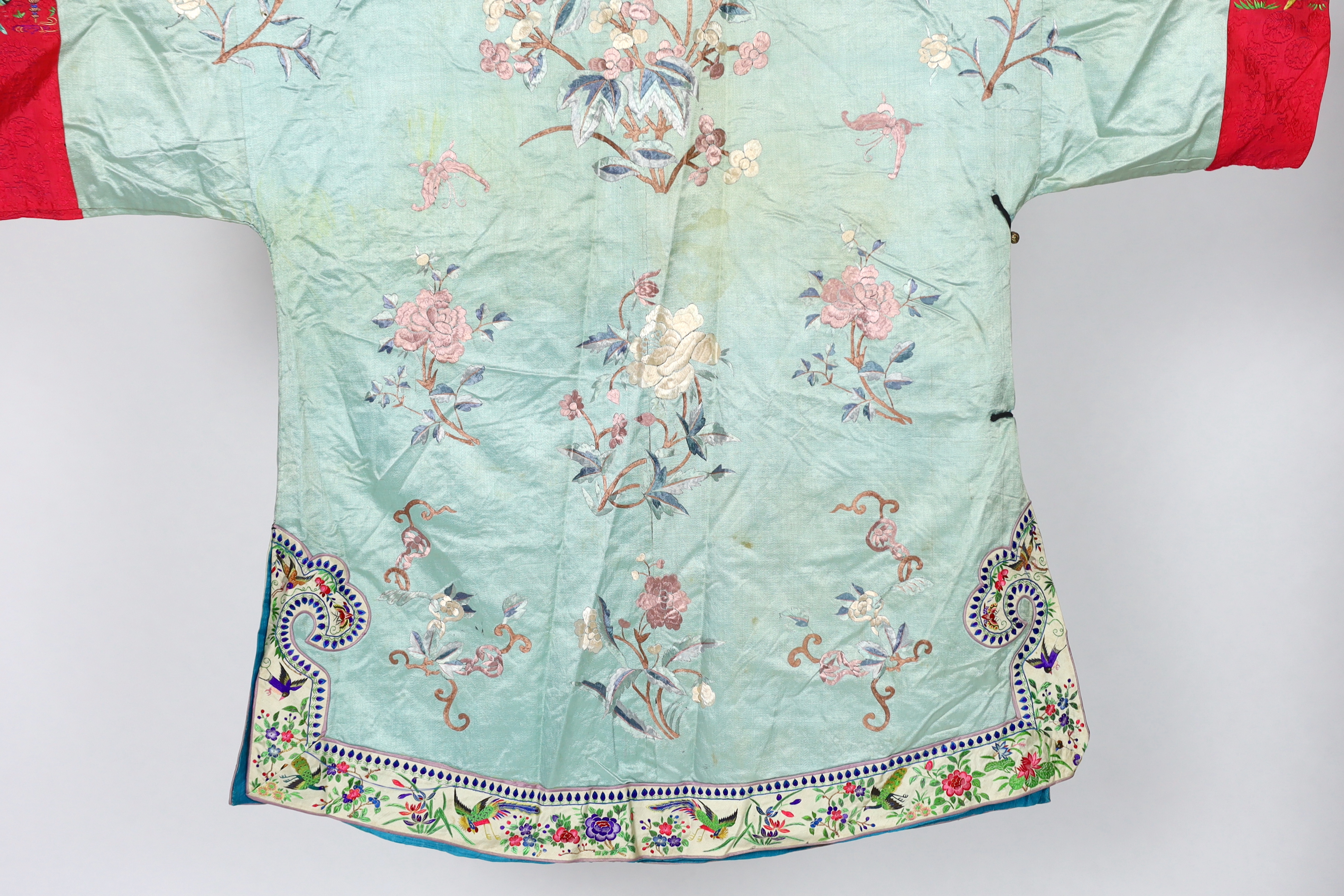 An early 20th century Chinese silk embroidered turquoise robe, embroidered in pastel silk with butterflies and flowers all over, polychrome embroidered braiding edged with lilac and bright pink sleeve bands embroidered w